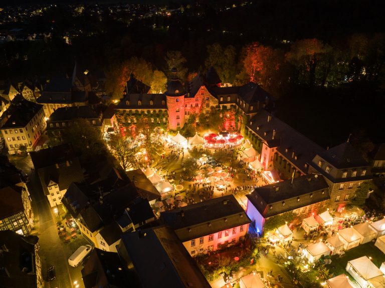 Blick auf den festlich beleuchteten Winterzauber im Schlosspark Laubach mit Besucherinnen und Besuchern zwischen weihnachtlich geschmückten Ständen.